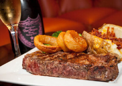 Perfectly cooked steak served with onion rings and a baked potato